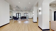 Located at 1220 S Tree Line Dr in Las Vegas, NV, this single-story commercial space offers a well-designed, open layout with a generous living room and a private office. The interior is defined by bright white walls, light hardwood-style flooring, and elegant arched doorways that lend a refined architectural character throughout.

The expansive living room serves as the centerpiece of the space, accommodating multiple seating arrangements with ease. Dual ceiling fans and recessed lighting keep the area bright and comfortable, while large black-framed French doors allow natural light to pour in and provide direct access to the exterior. A built-in fireplace anchors one end of the room, adding warmth and visual interest, while decorative arched niches and a mounted TV enhance the functional appeal. A bar-height counter with seating, a round dining area, and a bookshelf further define distinct zones within the open floor plan.

The private office is a compact, functional room equipped with a workstation and dedicated workspace, separated from the main area by a solid dark door for privacy.

Throughout the space, wall sconces, a sputnik-style chandelier, and ceiling fans provide layered lighting. The cohesive design—characterized by clean lines, neutral tones, and thoughtful detailing—creates a professional yet welcoming atmosphere well-suited for a variety of business uses.