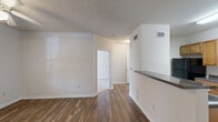 Located at 100 Walden Ln in Savannah, GA, this one-bedroom, one-bathroom residence offers a practical and comfortable single-floor layout. The combined kitchen and living area forms the heart of the home, with the living room featuring wood-look plank flooring, crown molding, a ceiling fan with light fixture, and a glass-panel door that opens to an outdoor balcony, allowing natural light to flow freely into the space. The kitchen is laid out in a galley style, equipped with warm honey-toned cabinetry, dark granite-style countertops, and black appliances including a refrigerator, electric range, built-in microwave, and dishwasher — all set atop matching wood-look flooring. The bedroom is a comfortable size, finished with plush wall-to-wall carpeting, a ceiling fan, and a window offering natural light and outdoor views. Two closets provide ample storage throughout the unit. The bathroom features a clean, white tub-shower combination with built-in shelving and chrome fixtures. Neutral tones and textured ceilings throughout the home create a calm, cohesive ambiance well-suited for comfortable everyday living in the heart of Savannah.