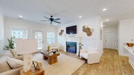 Located at 2968 Commonwealth Dr in Spring Hill, TN, this well-appointed single-story home offers a thoughtfully designed open-concept layout with two bedrooms and two bathrooms. Warm hardwood-style flooring flows throughout, complemented by crisp white walls, crown molding, and board-and-batten wainscoting that lend a refined modern farmhouse aesthetic.

The combined kitchen and living area serves as the heart of the home. The kitchen features white shaker cabinetry, stainless steel appliances, a large island with white countertops, and a sliding barn door accent. The adjoining living room centers around an electric fireplace framed by a clean-lined mantel and wainscoted surround, with French doors opening to the patio and filling the space with natural light.

The primary bedroom offers generous proportions, multiple windows, and a ceiling fan, creating a bright and comfortable retreat. The bathrooms are finished with white vanity cabinetry, updated lighting fixtures, and matching hardware throughout. Additional highlights include a dedicated laundry room, ample closet storage, and a private patio bordered by a stone retaining wall with open views. The entrance area features a stylish nook ideal for a home office, complete with wainscoting and pendant lighting.