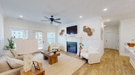 Located at 2968 Commonwealth Dr in Spring Hill, TN, this well-appointed single-story home offers a thoughtfully designed open-concept layout with two bedrooms and two bathrooms. Warm hardwood-style flooring flows throughout, complemented by crisp white walls, crown molding, and board-and-batten wainscoting that lend a refined modern farmhouse aesthetic.

The combined kitchen and living area serves as the heart of the home. The kitchen features white shaker cabinetry, stainless steel appliances, a large island with white countertops, and a sliding barn door accent. The adjoining living room centers around an electric fireplace framed by a clean-lined mantel and wainscoted surround, with French doors opening to the patio and filling the space with natural light.

The primary bedroom offers generous proportions, multiple windows, and a ceiling fan, creating a bright and comfortable retreat. The bathrooms are finished with white vanity cabinetry, updated lighting fixtures, and matching hardware throughout. Additional highlights include a dedicated laundry room, ample closet storage, and a private patio bordered by a stone retaining wall with open views. The entrance area features a stylish nook ideal for a home office, complete with wainscoting and pendant lighting.