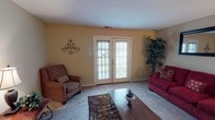 This two-story home offers a well-organized layout across two levels, providing comfortable living for its occupants. The main level features a carpeted living room bathed in natural light through a set of French doors that open to the outdoors, creating an inviting and airy atmosphere. The living area offers generous space for seating arrangements and flows naturally into the adjacent dining room, which features rich hardwood-style flooring, a window overlooking the exterior, and room for a full dining set. The kitchen is equipped with white cabinetry, stone-look countertops, and ample storage, combining practicality with a clean aesthetic. A half bath is conveniently located on this level. Upstairs, the two bedrooms are carpeted and each features a ceiling fan with lighting. The primary bedroom includes a closet and connects to the full bathroom, which is outfitted with a tiled tub-shower combination and hardwood-style flooring. The second bedroom provides comparable comfort and versatility. Warm, neutral wall tones are consistent throughout the home, contributing to a cohesive and welcoming ambiance across both floors.