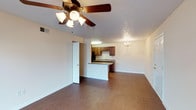 Located at Tanyard, this single-floor residence offers a well-designed layout that balances comfort and functionality. The open living area is finished with warm hardwood-style flooring and features a ceiling fan with light fixture overhead, creating a bright and airy atmosphere. A chandelier accents an adjacent dining area, while a sliding glass door brings in natural light and provides access to the outdoors. The kitchen is thoughtfully equipped with rich dark wood cabinetry, granite-style countertops, a double-basin sink, and black appliances including a refrigerator and range. A breakfast bar connects the kitchen to the living space, making it ideal for casual dining and entertaining. The bedrooms are carpeted for comfort, each featuring a ceiling fan, neutral wall tones, and windows that allow natural light to filter in. Two full bathrooms serve the residence, both outfitted with dark wood vanities, framed mirrors, bright vanity lighting, and hardwood-style flooring. One bathroom includes a full soaking tub and shower combination, while the other functions as a convenient half bath. Throughout the space, consistent finishes and a cohesive color palette create a clean, welcoming environment suited for everyday living.