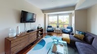 Located at 85 13th St in Boston's Charlestown neighborhood, this thoughtfully designed single-floor residence offers a comfortable and contemporary living experience. The open living room is anchored by rich hardwood floors, large windows that invite generous natural light and neighborhood views, and a welcoming layout ideal for both relaxing and entertaining. The galley-style kitchen is outfitted with stainless steel appliances, granite countertops, light wood cabinetry, and warm hardwood flooring, providing a functional and stylish space for cooking. Multiple carpeted bedrooms offer restful retreats, each featuring neutral tones, natural light from well-placed windows, and closet storage. The primary bedroom connects to a refined en-suite bathroom complete with a soaking tub, marble-style tile surround, dual-sink vanity with stone countertops, and tile flooring. A second full bathroom mirrors the clean, modern aesthetic with a tub/shower combination, stone-topped vanity, and tile floors. Throughout the residence, a cohesive neutral palette, modern finishes, and abundant natural light create a calm and inviting ambiance suited to contemporary urban living.