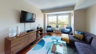 Located at 85 13th St in Boston's Charlestown neighborhood, this thoughtfully designed single-floor residence offers a comfortable and contemporary living experience. The open living room is anchored by rich hardwood floors, large windows that invite generous natural light and neighborhood views, and a welcoming layout ideal for both relaxing and entertaining. The galley-style kitchen is outfitted with stainless steel appliances, granite countertops, light wood cabinetry, and warm hardwood flooring, providing a functional and stylish space for cooking. Multiple carpeted bedrooms offer restful retreats, each featuring neutral tones, natural light from well-placed windows, and closet storage. The primary bedroom connects to a refined en-suite bathroom complete with a soaking tub, marble-style tile surround, dual-sink vanity with stone countertops, and tile flooring. A second full bathroom mirrors the clean, modern aesthetic with a tub/shower combination, stone-topped vanity, and tile floors. Throughout the residence, a cohesive neutral palette, modern finishes, and abundant natural light create a calm and inviting ambiance suited to contemporary urban living.