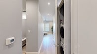 Located at 1825 Park Ave in Dallas, TX, this thoughtfully designed single-floor unit makes efficient use of its compact footprint without sacrificing style or functionality. Light wood-look flooring runs throughout, tying the space together with a clean, contemporary aesthetic.

The open-concept living and kitchen area serves as the heart of the unit. The living space features a wall-mounted electric fireplace flanked by large windows with horizontal blinds that invite natural light, complemented by a modern ceiling fan with recessed lighting above. The kitchen is outfitted with gray cabinetry, stainless steel appliances including a french door refrigerator and dishwasher, and a crisp white countertop with an integrated sink — all framed by a practical dining nook.

A hallway connects the main living area to the private bedroom and bathroom. The hallway also houses a stacked washer and dryer unit, providing convenient in-unit laundry. The bedroom is a calm retreat, finished in soft gray tones with recessed lighting and direct access to the bathroom. The bathroom features a glass-enclosed walk-in shower adorned with large hexagonal white tiles, a mosaic tile floor, and a clean white vanity, delivering a spa-like experience within a compact space.
