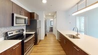 Located at 116 W 9th St in Wilmington, Delaware, this contemporary single-floor residence offers a well-designed layout with clean lines and a consistent modern aesthetic throughout. Warm hardwood-style flooring runs continuously across all rooms, lending cohesion and a welcoming feel to the space.

The open-concept kitchen is a standout feature, equipped with rich dark-wood cabinetry, stainless steel appliances including a refrigerator, electric range, and built-in microwave, as well as a light-toned countertop peninsula that doubles as a breakfast bar. A decorative tile backsplash adds a touch of texture. Pendant lighting illuminates the kitchen area, which flows seamlessly into the spacious living area.

The two bedrooms are bright and well-proportioned, each benefiting from large windows that bring in generous natural light and offer views of the surrounding urban streetscape. Both rooms include closet storage with sliding or bifold doors.

Two bathrooms serve the unit. The full bathroom features white subway tile surrounding a soaking tub and shower combination, paired with a dark-wood vanity and abundant storage. The second bathroom offers a floating vanity with a built-in sink, a tall storage cabinet, and a clean, minimalist finish. Both bathrooms continue the hardwood-style flooring found throughout the residence.