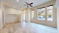 This well-appointed 2-bedroom, 1-bathroom residence offers a thoughtfully designed single-floor layout that maximizes both functionality and comfort. The open-concept living and dining area is a standout feature, boasting impressively tall ceilings, light wood-tone flooring throughout, and large windows that flood the space with natural light while offering outdoor views. A ceiling fan with a brushed gold finish adds both style and practicality to this bright, airy main living area.

The kitchen is a modern highlight, featuring a clean two-tone design with white upper cabinetry and warm wood lower cabinets, complemented by a suite of stainless steel appliances including a refrigerator, range, microwave, and dishwasher. Light countertops and under-cabinet lighting complete the polished look.

The primary bedroom features soaring ceilings, a ceiling fan, sliding closet doors, and frosted glass windows that allow natural light while maintaining privacy. The second bedroom also includes a closet and connects conveniently to the hallway. The full bathroom is equipped with a shower/tub combination and clean, neutral finishes. Additional conveniences include in-unit laundry, two closets, and a dedicated hallway connecting all rooms seamlessly.