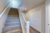 Located on a quiet court in Shelby Township, Michigan, this well-appointed 2-bedroom, 3-bathroom home spans three thoughtfully designed floors. The main living level features an open-concept layout combining the kitchen, dining room, and living room, all finished with light hardwood-style flooring. The kitchen is outfitted with gray shaker cabinets, dark granite countertops, stainless steel appliances including a range, microwave, dishwasher, and refrigerator, plus pendant lighting over the island. Sliding glass doors lead directly to the patio, offering serene water views and bringing natural light into the living area. Carpeted staircases with classic white wood railings connect all three floors. The upper level hosts both bedrooms, including a generously sized primary bedroom with a walk-in closet featuring wire shelving. The bathrooms are finished with wood-look flooring, gray vanities, and tub-shower combinations. A dedicated laundry room on the upper level includes a full-size washer and dryer with a utility sink and overhead shelving. The lower level provides a spacious basement, an attached garage with automatic opener, and ample closet storage throughout — totaling six closets across the home.