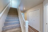 Located on a quiet court in Shelby Township, Michigan, this well-appointed 2-bedroom, 3-bathroom home spans three thoughtfully designed floors. The main living level features an open-concept layout combining the kitchen, dining room, and living room, all finished with light hardwood-style flooring. The kitchen is outfitted with gray shaker cabinets, dark granite countertops, stainless steel appliances including a range, microwave, dishwasher, and refrigerator, plus pendant lighting over the island. Sliding glass doors lead directly to the patio, offering serene water views and bringing natural light into the living area. Carpeted staircases with classic white wood railings connect all three floors. The upper level hosts both bedrooms, including a generously sized primary bedroom with a walk-in closet featuring wire shelving. The bathrooms are finished with wood-look flooring, gray vanities, and tub-shower combinations. A dedicated laundry room on the upper level includes a full-size washer and dryer with a utility sink and overhead shelving. The lower level provides a spacious basement, an attached garage with automatic opener, and ample closet storage throughout — totaling six closets across the home.