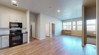 Located at 5050 Morrison Rd in Denver, CO, this single-floor, 3-bedroom, 2-bathroom residence offers a thoughtfully designed layout with modern finishes throughout. The open-concept living and kitchen area forms the heart of the home, featuring light hardwood-style flooring, elevated ceilings, and generous natural light from large windows. A standout built-in entryway nook with a bold green accent wall, shelving, and coat hooks adds a distinctive and functional touch to the living space.

The kitchen is well-equipped with white cabinetry reaching toward the ceiling, a herringbone tile backsplash, dark countertops, and black appliances including a refrigerator, electric range, microwave, and dishwasher. An in-unit laundry area is conveniently accessible from the kitchen.

The three bedrooms feature plush carpeting and neutral-toned walls, with some rooms benefiting from natural light through windows. Both bathrooms include hardwood-style flooring, vanities with dark countertops, and full tub-shower combinations. The overall ambiance is clean, modern, and move-in ready.
