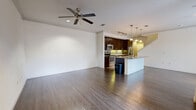 This three-bedroom, three-bathroom multi-story home in the Katy Ranch area of Houston, TX offers a well-organized layout spread across three floors. The ground level houses an attached garage with an automatic opener, providing convenient and secure parking. The main living floor features an open-concept kitchen and living room finished with rich hardwood-style flooring and crown molding throughout. The kitchen is appointed with dark espresso cabinetry, granite countertops, a subway tile backsplash, stainless steel appliances including a range and built-in microwave, and a peninsula with pendant lighting — ideal for casual dining or entertaining. Ceiling fans are present in the living areas, adding to everyday comfort. The uppermost floor is home to all three bedrooms, each carpeted and equipped with ceiling fans. The primary bedroom is generously sized, featuring a large window for natural light and direct access to a dedicated closet and en-suite bathroom. The additional bedrooms are well-proportioned with windows offering neighborhood views. Each bathroom features granite vanity countertops and dark cabinetry consistent with the home's design palette. Walk-in closets with built-in shelving provide ample storage throughout.