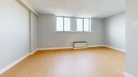 Located at 66 Mooregate Cres in Kitchener, Ontario, this well-appointed unit offers a thoughtfully organized single-floor layout that maximizes every square foot of available space. The open living area is finished with warm light wood laminate flooring and neutral grey walls, creating a clean and inviting atmosphere. A bank of horizontal windows runs along one wall, drawing in natural light while a baseboard heating unit ensures year-round comfort.

The kitchen is outfitted with crisp white cabinetry extending from floor to ceiling, paired with grey laminate countertops and a classic subway tile backsplash. A double stainless steel sink anchors the workspace, and the L-shaped layout provides generous storage and counter space for everyday use.

The hallways serve a functional role in the layout, with one featuring a set of full-width sliding closet doors that offer substantial built-in storage, contributing to the unit's organizational efficiency.

The bathroom is finished in a clean, all-white palette, complete with a full soaker tub and tiled surround, a toilet, and a vanity with a grey countertop and integrated sink, topped by a wall-mounted mirror. Tile flooring completes the polished, low-maintenance design. Overall, the unit presents a modern, neutral aesthetic well-suited for comfortable everyday living.