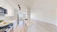 Located at 3030 Prospect St in Burlington, Ontario, this well-appointed 2-bedroom, 1-bathroom unit offers a thoughtfully designed layout with modern updates throughout. Light hardwood-style flooring flows seamlessly across every room, creating a clean and cohesive aesthetic.

The open-concept living room is generously sized, filled with natural light from large windows and a sliding glass door that leads to a private balcony. From the balcony, residents enjoy elevated views of the surrounding green canopy and neighbourhood skyline — a peaceful outdoor retreat.

The renovated galley kitchen is a standout feature, finished with sleek white cabinetry, glossy white tile backsplash, quartz countertops, stainless steel appliances including a built-in microwave, and a undermount sink. Track lighting adds a contemporary touch to the functional workspace.

Both bedrooms are bright and well-proportioned. The primary bedroom features mirrored sliding closet doors that enhance the sense of space, while the second bedroom benefits from a large window framing views of the lush surroundings.

The bathroom is finished in crisp white, featuring a tiled tub-shower surround, an undermount sink with modern cabinetry, and chrome fixtures. Clean lines and neutral tones define the overall ambiance of this move-in ready unit.