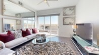 Located at 10650 Dean Martin Dr in Las Vegas, NV, this contemporary 2-bedroom, 2-bathroom residence offers a thoughtfully designed single-floor layout with a clean, modern aesthetic throughout. The open-concept living area seamlessly connects the kitchen, dining, and living spaces, all finished with rich dark hardwood-style flooring that contrasts beautifully against bright white walls and ceilings fitted with recessed lighting. The kitchen is appointed with sleek white cabinetry, dark countertops, stainless steel appliances including a gas range with a wall-mounted hood, a French door refrigerator, and a built-in microwave, complemented by white tile backsplash and open shelving. The living room features a ceiling fan and large sliding glass doors that invite abundant natural light and open to an outdoor balcony with expansive views. The primary bedroom includes a walk-in closet, private balcony access, and large windows framing outdoor views. The second bedroom also features a ceiling fan and comfortable proportions. Both bathrooms maintain the modern design language with dark countertops and hardwood-style flooring. Two hallways and two closets complete the well-organized floor plan, making this residence a well-appointed Las Vegas home.