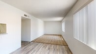 Located at 1975 W 36th St in Tucson, Arizona, this two-bedroom, one-bathroom single-story unit presents a clean, functional layout designed for comfortable everyday living. The open living area features wood-look plank flooring and a ceiling fan, flowing naturally toward a pass-through kitchen window that connects the two spaces. The galley-style kitchen is efficiently arranged with white cabinetry lining both sides, a stove, and a refrigerator, all set over matching wood-look flooring. A textured ceiling throughout adds a classic touch consistent with the unit's straightforward design. Both bedrooms are carpeted and bright, each featuring windows with vertical blinds that allow natural light while maintaining privacy. The primary bedroom offers a comfortable footprint with its own closet, and the unit includes a total of three closets for ample storage. The full bathroom is finished with wood-look flooring, a vanity with a lighted mirror, and a tub-shower combination. A connecting hallway links the bedrooms to the main living areas, keeping the layout cohesive. The crisp white walls and neutral tones throughout create a clean, move-in-ready atmosphere suited to a variety of living arrangements.