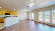 This single-story home at 929 Apollo Beach Blvd offers a well-designed, open-concept layout with consistent finishes throughout. The main living area is a spacious, light-filled space featuring warm hardwood-style flooring, a textured ceiling, and a ceiling fan with integrated lighting. Multiple French doors line the exterior wall, flooding the room with natural light and providing access to the outdoors. An adjacent dining area connects seamlessly to the kitchen, which is equipped with honey-toned wood cabinetry, granite-style countertops, stainless steel appliances including a range, microwave, and dishwasher, and light tile flooring. A breakfast bar provides additional counter space and casual seating.

The bedrooms are carpeted and bright, each featuring ceiling fans and windows with blinds that allow for natural light and outdoor views. Ample storage is provided through walk-in closets fitted with wire shelving systems. The bathrooms are finished with neutral tile flooring and walls. A secondary bathroom includes a vanity with a granite-style countertop and warm wood cabinetry, while the primary bathroom features a corner soaking tub and a separate glass-enclosed shower, both finished in coordinating beige tile. Overall, the home presents a cohesive, functional design suited to Florida living.