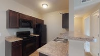 Located at 1108 Carriage Knoll Ln in Columbus, Ohio, this single-floor residence offers a thoughtfully designed open-concept layout that seamlessly connects the living and kitchen areas. The kitchen is well-appointed with rich dark espresso cabinetry, granite-style laminate countertops, and a full suite of black appliances including a refrigerator, electric range, and built-in microwave. Wood-look flooring runs throughout the kitchen, transitioning to plush neutral-toned carpet in the living and sleeping areas. A peninsula counter with pendant lighting creates a natural division between the kitchen and the open living space. The generous living area is a standout feature, highlighted by elegant French doors that invite abundant natural light and provide access to the outdoors. The bedroom is comfortably sized, offering a closet with sliding doors and a window that brings in additional natural light. The full bathroom is clean and functional, featuring a tub-shower combination, a vanity with dark cabinetry and a stone-look countertop, and tile flooring. Throughout the unit, neutral warm-toned walls and clean white trim create a bright, welcoming ambiance suited to a variety of personal styles.