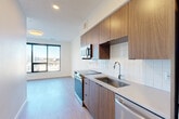 Located in Denver's RiNo neighborhood, this modern 3-bedroom, 1-bathroom residence offers a thoughtfully designed layout with contemporary finishes throughout. Light wood-look flooring runs seamlessly across the entire space, complementing the clean, minimalist aesthetic. The open kitchen is a standout feature, outfitted with warm wood-toned cabinetry, stainless steel appliances including a range, microwave, refrigerator, and dishwasher, along with a crisp white subway tile backsplash and quartz-style countertops. A large window at the end of the kitchen and living area floods the space with natural light while offering elevated views of the surrounding Denver cityscape. The three bedrooms are bright and well-proportioned, each benefiting from natural light; the primary bedroom features large floor-to-ceiling windows with sweeping city views and a spacious sliding-door closet with built-in wire shelving. The full bathroom is finished with white tile surround, a tub/shower combo, wood-toned vanity, and light flooring. A convenient stacked Samsung washer and dryer is tucked within a dedicated laundry closet, maximizing efficiency. Recessed lighting throughout adds to the clean, modern ambiance of this well-appointed Denver residence.