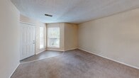 Located at 143 Stoneridge Dr in Columbia, SC, this one-bedroom, two-bathroom unit offers a practical and efficient single-floor layout. The living area greets you at the entry with a tiled foyer that transitions into wall-to-wall carpeting, creating a clear delineation between spaces. Natural light filters in through windows flanking the front door, keeping the room bright and welcoming. A textured ceiling runs throughout the unit, adding a classic touch to the neutral, warm-beige walls.

The kitchen is well-equipped with warm oak cabinetry providing ample storage, dark granite-style countertops, a double sink, and black appliances including an electric range and refrigerator. Wood-look flooring in the kitchen adds a modern contrast to the cabinetry. A hallway connects the main living areas to the bedroom and bathrooms, with additional storage accessible via interior doors.

The spacious bedroom features soft carpeting, a ceiling fan, and a sliding glass door that opens to an outdoor area, allowing for natural light and ventilation. Two bathrooms serve the unit, each featuring wood-look tile flooring, warm vanity cabinetry with dark countertops, and a full tub-shower combination with tiled surround.