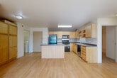 Located at 301 Second St E in Williston, North Dakota, this 2-bedroom, 1-bathroom unit offers a practical and well-organized single-floor layout. The open-concept living and kitchen area is anchored by light wood-look flooring that runs throughout the main living space, creating a bright and cohesive feel. The kitchen is well-appointed with light maple cabinetry, dark countertops, black appliances including a refrigerator, range, microwave, and dishwasher, and a central island that provides additional prep and storage space. Sliding glass doors in the living area open to a balcony, allowing natural light to fill the room. Both bedrooms feature neutral carpet flooring and receive natural light through windows with blinds. The primary bedroom includes a sliding closet and a baseboard heating unit, while the second bedroom offers a similarly comfortable layout. The full bathroom is finished with tile flooring, a light wood vanity, and a shower-tub combination. A dedicated in-unit laundry room with tile flooring adds everyday convenience. Two closets throughout the unit provide ample storage. A wall-mounted AC unit in the living area completes the climate control setup.