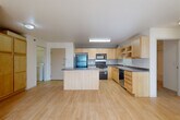 Located at 301 Second St E in Williston, North Dakota, this 2-bedroom, 1-bathroom unit offers a practical and well-organized single-floor layout. The open-concept living and kitchen area is anchored by light wood-look flooring that runs throughout the main living space, creating a bright and cohesive feel. The kitchen is well-appointed with light maple cabinetry, dark countertops, black appliances including a refrigerator, range, microwave, and dishwasher, and a central island that provides additional prep and storage space. Sliding glass doors in the living area open to a balcony, allowing natural light to fill the room. Both bedrooms feature neutral carpet flooring and receive natural light through windows with blinds. The primary bedroom includes a sliding closet and a baseboard heating unit, while the second bedroom offers a similarly comfortable layout. The full bathroom is finished with tile flooring, a light wood vanity, and a shower-tub combination. A dedicated in-unit laundry room with tile flooring adds everyday convenience. Two closets throughout the unit provide ample storage. A wall-mounted AC unit in the living area completes the climate control setup.