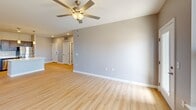 Located at 4005 State Farm Parkway in Columbia, Missouri, this well-appointed 2-bedroom, 2-bathroom unit offers a thoughtfully designed single-level layout with consistent light wood flooring and a neutral gray color palette throughout. The open-concept kitchen and living area serves as the heart of the unit, featuring a central island with a white quartz-style countertop, dark wood cabinetry, a full suite of stainless steel appliances including a refrigerator, range, microwave, and dishwasher, and pendant lighting above the island. The adjacent living room is generously proportioned, with a ceiling fan, natural light from large windows, and access to an outdoor balcony with exterior views. Both bedrooms are comfortably sized, each equipped with ceiling fans, large windows overlooking the surrounding area, and dedicated closets. The primary bedroom includes a walk-in closet fitted with multi-level shelving and hanging rods. Both bathrooms feature dark wood vanities with white countertops, large mirrors, and stylish light fixtures. The overall ambiance is clean, modern, and bright throughout.