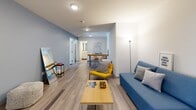 Located at 253 College Street in the heart of downtown Toronto, this well-appointed 4-bedroom, 2-bathroom unit offers a smart, efficiently designed layout across a single floor. The open-concept living area serves as the communal hub of the unit, featuring light wood-effect flooring, soft blue accent walls, and clean white ceilings that create a bright, welcoming atmosphere. The living space comfortably accommodates seating and a dining area, flowing naturally into the hallways that connect to the private bedrooms.

Each of the four bedrooms is thoughtfully designed with plush carpeting, built-in wood shelving and wardrobe storage, a dedicated study desk, and large windows that invite natural light and frame views of the Toronto skyline. The primary bedroom offers a notably generous footprint compared to the others, with additional closet space.

The two bathrooms are finished in a clean, modern style with light wood-effect tile flooring, white cabinetry, and walk-in shower stalls with curtain enclosures and brushed nickel fixtures. Two hallways connect the shared and private spaces, ensuring a practical flow throughout the unit. The overall aesthetic is contemporary and functional, well-suited for shared living in one of Toronto's most walkable and dynamic urban neighbourhoods.
