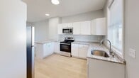 This thoughtfully designed 3-bedroom, 2-bathroom unit at 33-35 Rowe Ave in Hartford, CT offers a clean, modern aesthetic throughout its single-story layout. Light hardwood flooring runs consistently through the main living areas and all three bedrooms, contributing to a bright, cohesive feel.

The kitchen is a standout feature, equipped with white shaker cabinetry, granite countertops, stainless steel appliances including a range, microwave, dishwasher, and refrigerator, and a peninsula that provides additional prep and seating space. Recessed lighting and a window at the far end keep the space well-lit and functional.

Each of the three bedrooms features light hardwood floors, neutral gray walls, and individual wall-mounted mini-split units for climate control. Windows in each room allow natural light to filter in throughout the day. The primary bedroom offers a comfortable footprint suitable for standard furnishings.

The two bathrooms differ notably in finish. One features dark slate-toned floor and accent tiles with a walk-in shower, while the second presents a more refined look with marble-style porcelain tile covering the floors and shower surround. Both include white vanities and a window for natural ventilation. Two hallways connect the rooms efficiently, completing a practical and well-appointed layout.