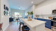 Located at 525 E 21st St in Charlotte's vibrant 28205 corridor, this single-floor residence offers a thoughtfully designed open-concept layout that seamlessly connects the kitchen, dining, and living areas. The kitchen is a standout feature, showcasing a striking two-tone design with bold navy-blue lower cabinetry, crisp white upper cabinets, a white quartz countertop island with bar seating, subway tile backsplash, and a full suite of stainless steel appliances. Light wood-look flooring runs throughout the main living areas, enhancing the bright, airy atmosphere created by large windows that invite abundant natural light. The living area offers a comfortable, well-proportioned space with room for seating and accent décor. Two bedrooms provide restful retreats, each with plush carpeting and windows overlooking the surroundings. The primary bathroom features a walk-in glass shower, a dedicated walk-in closet, and a navy vanity with white countertop. A second full bathroom mirrors the cohesive design aesthetic, complete with a soaking tub, subway tile surround, and a wide vanity mirror. The overall ambiance is clean, contemporary, and welcoming throughout.