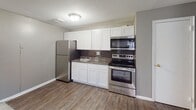 Located at 2800 Welsh Rd in the Northeast Philadelphia neighborhood of PA 19152, this single-floor unit offers a functional and straightforward layout designed for comfortable everyday living. The open living and dining area is finished with neutral gray walls and plush wall-to-wall carpeting, creating a clean and cohesive atmosphere throughout. The kitchen is positioned directly off the living area and features a modern design with white shaker-style cabinetry, dark granite-look countertops, a dark tile backsplash, and wood-look vinyl flooring. It is fully equipped with stainless steel appliances, including a refrigerator, electric range, built-in microwave, and a single-basin sink. The bedrooms are generously sized, each carpeted and painted in a calm gray tone. Multiple windows allow natural light to filter in, and each bedroom is equipped with a wall-mounted air conditioning unit and baseboard heating for year-round climate control. The bathroom includes a full-size soaking tub with a shower and a clean white surround. The unit's layout, as visible in the floor plan, flows efficiently from the entry door through the living space and into the private rooms, offering a practical and well-organized living environment.