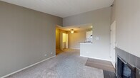 This single-floor residence at 235 N Oakhurst Dr in Aurora, IL offers a thoughtfully laid-out interior with a neutral color palette of warm gray tones throughout. The open-concept living and dining area is generously proportioned, featuring plush wall-to-wall carpeting, elevated ceilings, and a seamless transition to the kitchen via a half-wall breakfast bar with a laminate countertop. A large sliding glass door with vertical blinds floods the living area with natural light and provides outdoor views, while a ceiling fan adds functional comfort.

The kitchen is well-appointed with white cabinetry, granite-style countertops, a classic subway tile backsplash, and stainless steel appliances including a refrigerator, range, and over-the-range microwave. Wood-look flooring grounds the kitchen space, contrasting neatly with the carpeted living areas.

The bedrooms are comfortably sized, each featuring plush carpeting, ceiling fans, and windows that allow natural light. The bathroom includes a full tub and shower combination, a toilet, and earthy stone-look tile flooring. A laundry area is also present within the unit, adding everyday convenience to this well-organized single-level home.