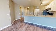 This one-bedroom, one-bathroom unit in Clinton, Mississippi offers a thoughtfully designed single-floor layout that maximizes its compact footprint. The open-concept kitchen and living area forms the heart of the space, anchored by a central kitchen island with a light quartz countertop and undermount sink. The kitchen is equipped with a full suite of stainless steel appliances, including a french door refrigerator, range, microwave, and dishwasher, complemented by white shaker cabinetry and a subway tile backsplash. Track lighting overhead and wood-style plank flooring throughout the main living area create a clean, contemporary atmosphere. The living room features neutral warm-toned walls and ample wall space, providing flexibility for various furniture arrangements. The bedroom is carpeted for comfort and features a ceiling fan, a large window with blinds that admits generous natural light, and a dedicated closet for storage. The bathroom is finished with a white vanity featuring brushed nickel hardware, a framed mirror, tile flooring, and a full tub-shower combination enclosed with classic white subway tile. Overall, the unit presents a modern, move-in-ready aesthetic with consistent neutral tones and quality finishes throughout.