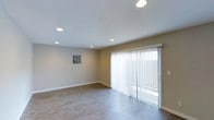 Unit #27 at 3131 Cauby in San Diego is a single-floor residence that combines clean, modern design with functional living spaces. The interior features a consistent, neutral color palette with warm beige walls and light wood-look flooring throughout, creating a cohesive and inviting atmosphere.

The living area is open and well-proportioned, illuminated by recessed lighting embedded in the smooth white ceiling. A full-width sliding glass door fitted with sheer vertical blinds allows natural light to fill the space while providing access to the outdoors. The layout offers flexibility for a variety of furnishing arrangements.

The kitchen is thoughtfully designed and well-appointed, featuring crisp white shaker-style cabinetry that extends to ceiling height, maximizing storage capacity. Granite-style countertops provide durable and attractive workspace, while the suite of stainless steel appliances — including a French door refrigerator with water and ice dispenser, an electric range, and a built-in microwave — elevates the kitchen's functionality. Recessed lighting overhead ensures the space is bright and practical. The kitchen flows naturally into the adjoining living areas, supporting an open, connected feel throughout this single-level residence.