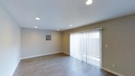Unit #27 at 3131 Cauby in San Diego is a single-floor residence that combines clean, modern design with functional living spaces. The interior features a consistent, neutral color palette with warm beige walls and light wood-look flooring throughout, creating a cohesive and inviting atmosphere.

The living area is open and well-proportioned, illuminated by recessed lighting embedded in the smooth white ceiling. A full-width sliding glass door fitted with sheer vertical blinds allows natural light to fill the space while providing access to the outdoors. The layout offers flexibility for a variety of furnishing arrangements.

The kitchen is thoughtfully designed and well-appointed, featuring crisp white shaker-style cabinetry that extends to ceiling height, maximizing storage capacity. Granite-style countertops provide durable and attractive workspace, while the suite of stainless steel appliances — including a French door refrigerator with water and ice dispenser, an electric range, and a built-in microwave — elevates the kitchen's functionality. Recessed lighting overhead ensures the space is bright and practical. The kitchen flows naturally into the adjoining living areas, supporting an open, connected feel throughout this single-level residence.