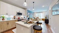 Located at 2010 N Brevard St in Charlotte, NC, this single-floor residence offers a thoughtfully designed open-concept layout with contemporary finishes throughout. The kitchen serves as the heart of the home, featuring a large central island with quartz countertops and bar seating, a full suite of stainless steel appliances, and a stylish mix of white upper cabinetry paired with warm wood-toned lower cabinets. A classic white subway tile backsplash and pendant lighting complete the space. Hardwood flooring flows seamlessly from the kitchen into the living area, where large windows allow abundant natural light and provide views of the surrounding neighborhood. The living room is defined by a muted blue accent wall and an inviting atmosphere well-suited for both relaxing and entertaining. The bedroom continues the bold design aesthetic with a rich teal accent wall, plush carpeting, and generous natural light from a sizable window. The bathroom is clean and modern, finished with large-format tile flooring, a wood-toned vanity, and a glass-enclosed walk-in shower clad in crisp white tile with matte black hardware accents. Every detail of this residence reflects a cohesive, contemporary design sensibility.