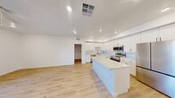 Located at 2555 N Rancho Dr in Las Vegas, Nevada, this thoughtfully designed 2-bedroom, 2-bathroom residence offers a clean, contemporary aesthetic throughout its well-appointed single-floor layout. Light wood-tone flooring flows seamlessly through every room, complemented by crisp white walls and recessed lighting that create a bright, airy atmosphere.

The open-concept kitchen and living area serves as the heart of the home, showcasing a large center island with a marble-style quartz countertop, white shaker cabinetry extending to the ceiling, a subway tile backsplash, and a full suite of stainless steel appliances including a refrigerator, range, microwave, and dishwasher. A wide hallway connects the main living area to the private quarters.

Both bedrooms are generously proportioned, each featuring ceiling fans, natural light, and sliding glass doors that open to a balcony with open views of the surrounding Las Vegas community. The primary bedroom includes a dedicated closet with sliding panel doors. The second bedroom also offers closet storage and a window with a roller shade.

The two bathrooms feature white vanities with stone-topped counters, tub-shower combinations with tile surrounds, and chrome fixtures. A dedicated laundry room houses a full-size washer and dryer with overhead shelving, adding exceptional in-unit convenience to this move-in-ready Las Vegas residence.