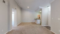 This single-story, 3-bedroom, 2-bathroom home offers a thoughtfully designed layout that maximizes comfort and functionality. The living room features vaulted ceilings adorned with crown molding, a ceiling fan, and soft carpeting, creating a warm and inviting atmosphere. A peninsula with dark granite countertops connects the living area to the kitchen, which is equipped with stainless steel appliances — including a refrigerator, range, and microwave — complemented by white cabinetry and wood-look flooring. The primary bedroom is a generously sized retreat with a ceiling fan, crown molding, plush carpet, and sliding glass doors that open to an outdoor view with natural greenery. It is accompanied by a spacious walk-in closet fitted with wire shelving. The additional bedrooms are carpeted and bright, each featuring ceiling fans and access to closet storage. The bathrooms are clean and functional, with one featuring a tub-shower combination and wood-look flooring. A dedicated laundry area with overhead wire shelving provides added convenience. Throughout the home, neutral tones, consistent crown molding details, and recessed lighting contribute to a cohesive and polished aesthetic.