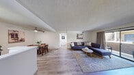 Located at 3333 N Michael Way in Las Vegas, NV, this 2-bedroom, 1-bathroom single-floor residence offers a practical and well-organized layout across a comfortable footprint. The open-concept living and dining area forms the heart of the home, featuring light wood-style flooring, neutral walls, and a textured ceiling throughout. The living room is generously sized, accommodating a large sectional sofa, and benefits from a sliding glass door that opens to a private outdoor patio, allowing natural light to filter in. A ceiling fan adds comfort to the space. The dining area sits adjacent to the kitchen and features its own ceiling fan with a pendant light, creating a defined yet connected space for meals. The kitchen is efficiently designed with white cabinetry, white appliances, and a pass-through counter that bridges the kitchen and dining areas. Both bedrooms are bright and serene, each with large windows fitted with blinds, light flooring, and textured ceilings. The primary bedroom offers a comfortable footprint with ample wall space. Two closets provide solid storage throughout. The bathroom features a clean, full-sized tub-shower combination. A hallway connects the private areas of the home, completing this well-rounded residential layout.