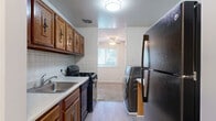 Located at 6112 Edsall Rd in Alexandria, Virginia, this one-bedroom, one-bathroom residence offers a well-organized single-level layout with a thoughtful arrangement of living spaces. The living room serves as the heart of the home, featuring neutral carpet flooring, bright white walls, and expansive sliding glass doors that open onto a private balcony, flooding the space with natural light and providing views of lush greenery outside. Adjacent to the living area, the dining room benefits from a ceiling fan and an additional window that continues the theme of natural light throughout. The galley-style kitchen is outfitted with warm wood cabinetry, a white tile backsplash, light countertops, and black appliances including a gas range and refrigerator. Light vinyl flooring runs through the kitchen, which also accommodates an in-unit washer and dryer. The spacious primary bedroom offers comfortable carpet flooring and a well-sized window providing natural light. Two closets contribute to the home's practical storage solutions. The bathroom features a clean, fully tiled shower and tub combination. A dedicated entrance and hallway complete this efficiently designed residence in a convenient Alexandria location.