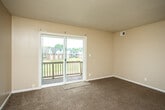 This single-floor unit offers a practical and straightforward layout designed for comfortable everyday living. The kitchen is equipped with dark wood cabinetry, light-toned countertops, stainless steel appliances including a refrigerator and electric range, and a double-basin sink. Hardwood-style flooring runs throughout the kitchen, transitioning to carpet in the adjoining living area. The living room is generously sized, featuring a textured ceiling, neutral warm-toned walls, and a sliding glass door that opens to a private balcony with outdoor views of the surrounding neighborhood.

The unit includes multiple bedrooms, each finished with wall-to-wall carpet, neutral paint, and windows that invite natural light. One bedroom features a built-in closet with a rod and shelf system, providing practical storage. The layout, as seen in the floor plan overview, clearly separates the sleeping areas from the main living and kitchen spaces.

The bathroom includes a full-size soaking tub with a tiled surround and a standard toilet, finished in clean white tones. Throughout the unit, consistent warm beige walls, textured ceilings, and carpeted flooring create a cohesive and understated aesthetic.