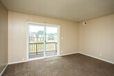 This single-floor unit offers a practical and straightforward layout designed for comfortable everyday living. The kitchen is equipped with dark wood cabinetry, light-toned countertops, stainless steel appliances including a refrigerator and electric range, and a double-basin sink. Hardwood-style flooring runs throughout the kitchen, transitioning to carpet in the adjoining living area. The living room is generously sized, featuring a textured ceiling, neutral warm-toned walls, and a sliding glass door that opens to a private balcony with outdoor views of the surrounding neighborhood.

The unit includes multiple bedrooms, each finished with wall-to-wall carpet, neutral paint, and windows that invite natural light. One bedroom features a built-in closet with a rod and shelf system, providing practical storage. The layout, as seen in the floor plan overview, clearly separates the sleeping areas from the main living and kitchen spaces.

The bathroom includes a full-size soaking tub with a tiled surround and a standard toilet, finished in clean white tones. Throughout the unit, consistent warm beige walls, textured ceilings, and carpeted flooring create a cohesive and understated aesthetic.