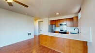 This well-appointed 2-bedroom, 1-bathroom residence is laid out on a single floor, offering a functional and comfortable living environment. The open-concept kitchen and living room serve as the heart of the home, where warm-toned hardwood-style flooring flows seamlessly throughout. The kitchen is equipped with stainless steel appliances — including a refrigerator, electric range, and over-the-range microwave — complemented by rich wood cabinetry, a clean white countertop, and a peninsula that provides additional workspace and a natural divide between the kitchen and living areas. A ceiling fan in the living room adds comfort, while large floor-to-ceiling windows and a sliding glass door lead to a private balcony overlooking a vibrant urban streetscape. Both bedrooms are bright and well-sized, with the primary bedroom featuring a closet with built-in shelving. The secondary bedroom benefits from a large window with city views. A hallway connects the main living areas to the bedrooms and the full bathroom, which features a wood vanity with a white countertop, light flooring, and clean, neutral finishes. A dedicated closet provides additional storage within the unit.