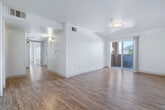This single-story, 3-bedroom, 2-bathroom home offers a practical and comfortable layout designed to maximize everyday living. The interior features consistent wood-style flooring throughout, creating a cohesive and easy-to-maintain living environment. Warm neutral wall tones and flush-mount lighting contribute to a bright, clean ambiance across all rooms.

The kitchen is equipped with white cabinetry, a gas range, over-the-range microwave, and a full-size refrigerator, all in white appliances. A peninsula counter provides additional prep space and defines the transition between the kitchen and the adjacent living area. Notably, an in-unit washer and dryer are conveniently located just off the kitchen.

The living room is open and airy, featuring a sliding glass door that allows natural light to pour in and provides outdoor views of the surrounding landscaped area. The primary bedroom is a comfortable size and includes access to a dedicated walk-in closet outfitted with wire shelving systems for organized storage. The two bathrooms are finished with white cabinetry, light countertops, and tub-shower combinations. Additional windows fitted with vertical blinds bring natural light into the bedrooms while maintaining privacy. A hallway connects the rooms, completing this well-organized and move-in-ready home.