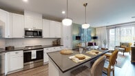 This single-story residence in Germantown, Tennessee, offers a thoughtfully designed open-concept layout that seamlessly connects the kitchen, dining, and living areas. The kitchen is a standout feature, equipped with white shaker-style cabinetry, dark granite countertops, a subway tile backsplash, and a full suite of stainless steel appliances. A central island with an undermount sink and pendant lighting above provides both additional prep space and casual seating, making it ideal for entertaining.

The living area features sage green accent walls and large sliding glass doors that invite abundant natural light while offering direct access to an outdoor space with views of the surrounding community. The bedroom is a comfortable retreat with plush carpeting, a ceiling fan, and generous windows dressed with layered curtains that allow for flexible light control.

The bathroom is finished with a granite-topped vanity, white cabinetry, and tile flooring. A doorway leads directly into a dedicated walk-in closet with built-in shelving, adding practical storage. Wood-look flooring flows through the main living areas, tying the space together with a warm, cohesive aesthetic throughout.