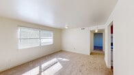 Located at 1830 Fant Dr in Fort Oglethorpe, Georgia, this single-story home offers a straightforward and functional layout spread across one level. The living area is generously sized, featuring neutral-toned wall-to-wall carpeting and a large window fitted with horizontal blinds that allows ample natural light to fill the room. The bright, clean walls and flush-mount ceiling lighting give the space a simple, understated character.

The kitchen is equipped with warm wood-toned cabinetry providing considerable storage, laminate countertops, a double-basin sink, and a white electric range and refrigerator. A window above the counter brings in natural light, and the tile flooring adds a practical, easy-to-maintain surface.

The bedrooms continue the home's consistent aesthetic, each featuring carpet flooring, white walls, and windows with blinds. One bedroom includes closet access and connects to the hallway, while another offers a closet and direct access to the rest of the home. The bathroom features tile flooring, a walk-in shower stall with grab bars, and a toilet, presenting a clean and accessible design.

Overall, this home offers a clean, functional living environment with a neutral palette throughout, suitable for comfortable everyday living in the Fort Oglethorpe community.