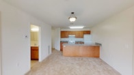This single-floor residence offers a well-organized and functional layout designed for comfortable everyday living. The open-concept kitchen and living area serve as the heart of the space, featuring warm honey-toned wood cabinetry, granite-patterned countertops, and a peninsula island with a sink — ideal for both meal preparation and casual dining. White appliances, including a coil-burner range and refrigerator, complete the kitchen. Soft, neutral carpeting flows throughout the living and bedroom areas, contributing to a cohesive and understated aesthetic.

The bedrooms are generously proportioned, each featuring large windows that invite natural light and offer views of the surrounding exterior. The clean, neutral walls provide a versatile backdrop adaptable to a variety of furnishing styles.

Two full bathrooms serve the residence. One features a shower-tub combination, while the other — likely an en-suite — offers a walk-in glass-enclosed shower stall, a wood-cabinet vanity with a single sink, and a well-lit mirror. Both bathrooms feature light tile flooring and maintain a clean, functional design.

Overall, the space presents a straightforward and practical layout with consistent finishes throughout, making it an accessible and move-in ready residence.