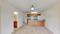 This single-floor residence offers a well-organized and functional layout designed for comfortable everyday living. The open-concept kitchen and living area serve as the heart of the space, featuring warm honey-toned wood cabinetry, granite-patterned countertops, and a peninsula island with a sink — ideal for both meal preparation and casual dining. White appliances, including a coil-burner range and refrigerator, complete the kitchen. Soft, neutral carpeting flows throughout the living and bedroom areas, contributing to a cohesive and understated aesthetic.

The bedrooms are generously proportioned, each featuring large windows that invite natural light and offer views of the surrounding exterior. The clean, neutral walls provide a versatile backdrop adaptable to a variety of furnishing styles.

Two full bathrooms serve the residence. One features a shower-tub combination, while the other — likely an en-suite — offers a walk-in glass-enclosed shower stall, a wood-cabinet vanity with a single sink, and a well-lit mirror. Both bathrooms feature light tile flooring and maintain a clean, functional design.

Overall, the space presents a straightforward and practical layout with consistent finishes throughout, making it an accessible and move-in ready residence.