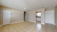 Located at 1705 17th Ave N in Saint Petersburg, Florida, this single-story home offers a straightforward and functional layout finished consistently with light beige ceramic tile flooring throughout every room. The interior is painted in warm neutral tones, contributing to a bright and cohesive atmosphere across the living spaces.

The main living area is generously proportioned, featuring large windows fitted with horizontal blinds that allow ample natural light to fill the space. A textured ceiling adds subtle visual detail overhead, while clean white baseboards frame the floors throughout. The open layout connects the living area to additional rooms with ease, creating a practical flow through the home.

The kitchen is efficiently arranged with white cabinetry, dark countertops, a double-basin sink positioned beneath a window, and white appliances including a refrigerator, electric range, and over-the-range microwave. Adjacent rooms serve as bedrooms, each benefiting from one or more windows that bring in natural light and provide ventilation.

The bathroom is cleanly appointed with a white vanity, a wall-mounted light fixture, a window for natural light, and a full tub-shower combination. Throughout the home, the consistent use of tile flooring, neutral walls, and white trim creates a unified, easy-to-maintain interior.