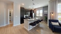 Located at 115 Great Lawn Dr in Summerville, SC, this single-floor residence offers a well-designed layout with a cohesive, contemporary aesthetic. The kitchen serves as a central highlight, featuring dark espresso cabinetry, granite countertops, stainless steel appliances, a subway tile backsplash, and a spacious island with pendant lighting and bar seating — ideal for both meal prep and casual dining. Light wood-look flooring flows through the main living and kitchen areas, complementing the neutral gray and taupe color palette found throughout the home. The hallway entrance sets an inviting tone, accented by large-format wall art and recessed lighting that guides visitors toward the main living spaces. The bedrooms are carpeted for comfort, each benefiting from natural light through well-sized windows dressed with sheer curtains and blinds. The bathrooms are thoughtfully appointed with dark vanity cabinetry, granite countertops, and tub-shower combinations with tiled surrounds and light wood-look flooring. A dedicated laundry room houses a full-size washer and dryer with overhead shelving for added storage. The 3D dollhouse view reveals a practical and well-proportioned floor plan that balances open communal spaces with private retreats, making this home functional and comfortable for everyday living.