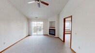 This single-floor residence offers a well-organized layout designed for comfortable everyday living. The spacious living room serves as the centerpiece of the home, showcasing dramatic vaulted ceilings, plush wall-to-wall carpeting, and a ceiling fan that enhances airflow throughout. A corner gas fireplace with a built-in niche above adds both warmth and character, while sliding glass doors flood the room with natural light and provide direct access to an outdoor balcony or patio. The adjacent dining area connects seamlessly to the kitchen via a convenient pass-through window, complemented by a decorative pendant light fixture. The kitchen is well-appointed with warm oak cabinetry, white appliances including a refrigerator, electric range, built-in microwave, and dishwasher, along with light tile flooring and ample counter space. The bedrooms are generously sized, each featuring soft carpeting, neutral walls, and windows that bring in natural views of surrounding greenery. One bedroom includes a closet with oak doors for added storage. Two full bathrooms serve the home, each finished with oak vanities, light tile flooring, large mirrors, and vanity lighting, providing a clean and functional design throughout.